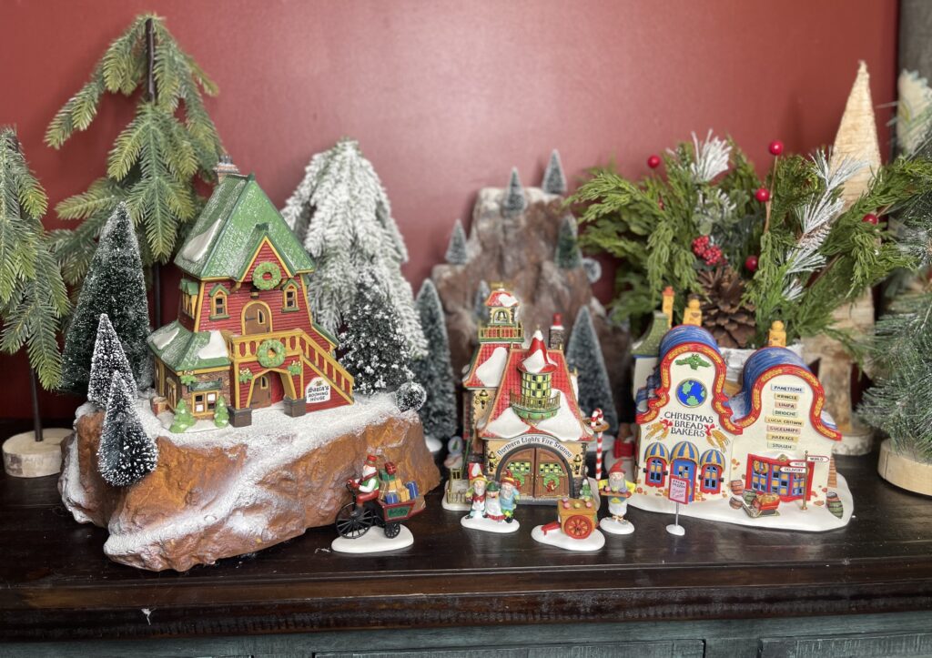 Shows step 4 of setting up a small Christmas village display: adding trees and evergreens
