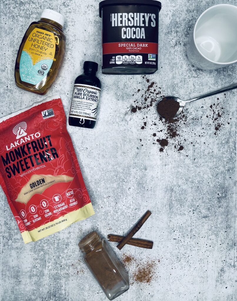 a picture of all the ingredients used to make healing hot cocoa. Hot Cocoa Powder, Vanilla extract, honey, Monk Fruit Sweetener and cinnamon. 
